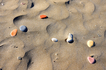 Stones on sand at beach. Sea stones background at seashore. Colored stone on coastline. Stone on sand background at sea beach. Pebbles at coast. Pebble as abstract natural background. Sea stones. .