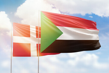Sunny blue sky and flags of sudan and denmark