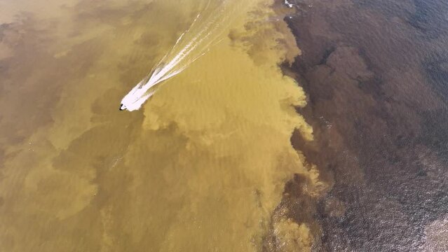 Boat sailing at Meeting of the Waters tourism landmark at Manaus Amazonas Brazil. Brown Amazon river side Black Negro River with two different colors. Amazon rainforest Brazil. Manaus Amazonas Brazil.