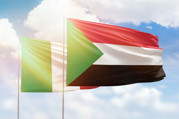 Sunny blue sky and flags of sudan and italy