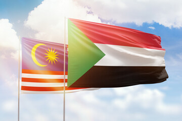 Sunny blue sky and flags of sudan and malaysia