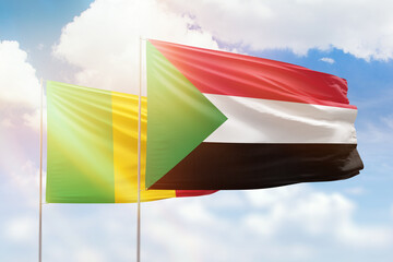 Sunny blue sky and flags of sudan and mali