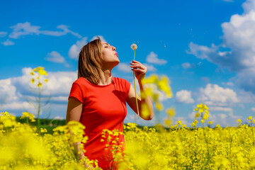 Young pretty woman in a colored dress on Lightning cheerful yellow background blooming rapeseed...