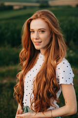 Portrait of a ginger woman with long hair, looking at camera, standing outdoors. Attractive...