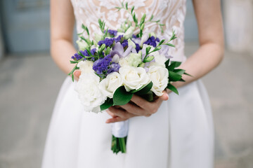 Obraz na płótnie Canvas Wedding bouquet with white and violet roses in hands of beautiful bride in retro stylish wedding dress. Selective focus. High quality photo.