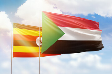 Sunny blue sky and flags of sudan and uganda