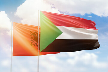 Sunny blue sky and flags of sudan and albania