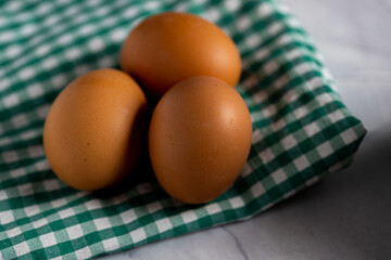 fresh eggs on a green checkered gingham tablecloth. close up close shot.