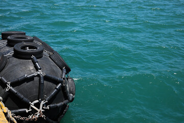Black floating fender in sea on sunny day