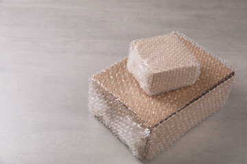 Cardboard boxes covered with bubble wrap on light grey table. Space for text