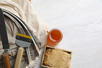 Different beekeeping tools and jar of honey on white table, flat lay. Space for text