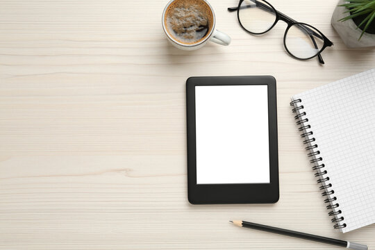 Flat lay composition with modern e-book reader on white wooden table, space for text