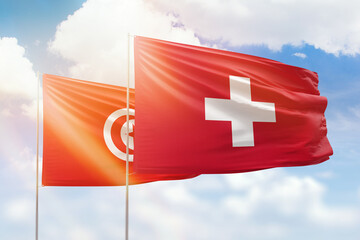 Sunny blue sky and flags of switzerland and tunisia