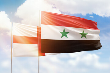 Sunny blue sky and flags of syria and england