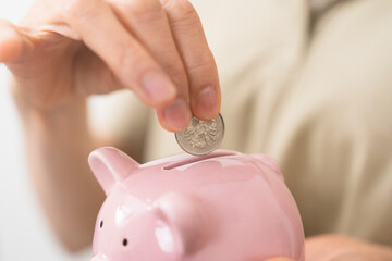 貯金箱にお金を入れるミドル女性
