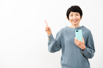スマートフォンを持ちながら指差しをするミドル女性