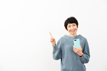 スマートフォンを持ちながら指差しをするミドル女性