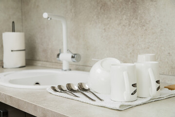 Dry towel and clean dishware on white countertop near sink in kitchen