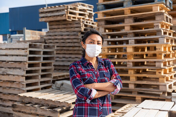 Woman manager in protective mask keeps records of building materials in the open area of a construction store
