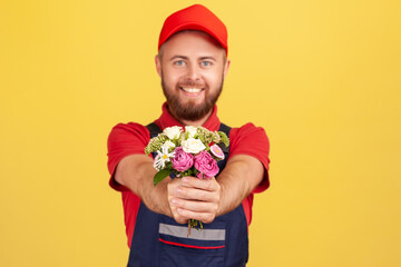 Portrait of positive satisfied bearded delivery man giving bouquet of flowers, bringing order,...