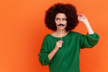 Pensive woman with Afro hairstyle wearing green casual style sweater having festive mood, standing...