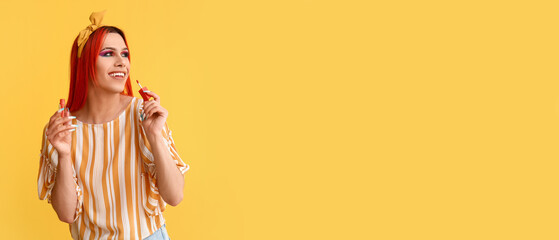 Stylish transgender woman applying lipstick on yellow background with space for text - obrazy, fototapety, plakaty