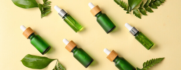 Many bottles of natural cosmetic serum and essential oils on color background, top view