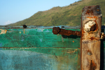 Dark green wooden planks as part of the hull with rusty bolt                                