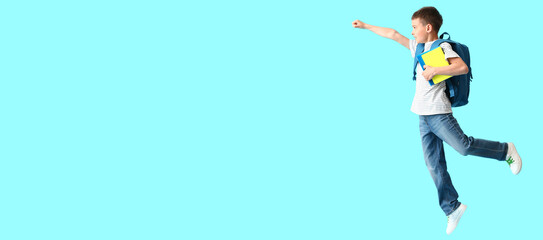 Little jumping schoolboy on light blue background with space for text
