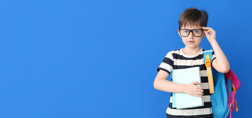Cute little schoolboy on blue background with space for text