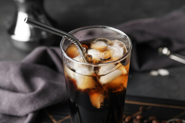 Glass with cold brew coffee and metal straw on dark background, closeup