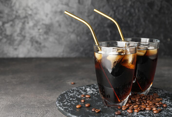 Board with glasses of cold brew coffee and metal straws on dark background
