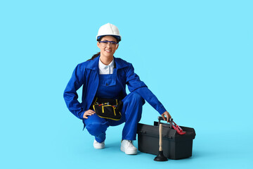 Asian female plumber with bags on blue background