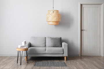 Comfortable sofa, table and modern lamp near grey wall