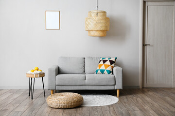 Comfortable sofa, table and modern lamp near grey wall