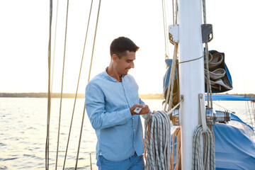 Obraz premium Young man adjusting the rigging of his yacht