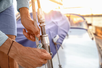 Young man adjusting the rigging of his yacht