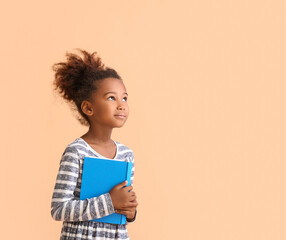 Little African-American girl with book on beige background