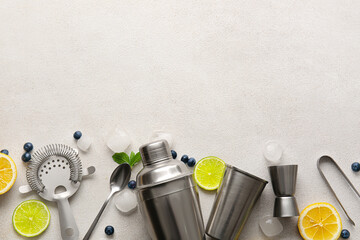 Set of bartender utensils and cocktail ingredients on light background