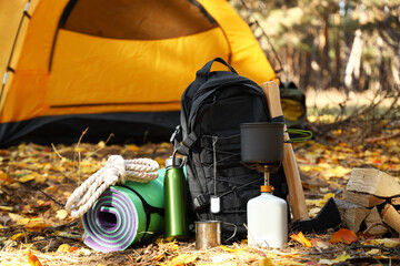 Toeristenoverlevingspakket en kampeertent in herfstbos
