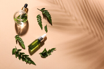 Bottles of natural serum and fern leaves on color background