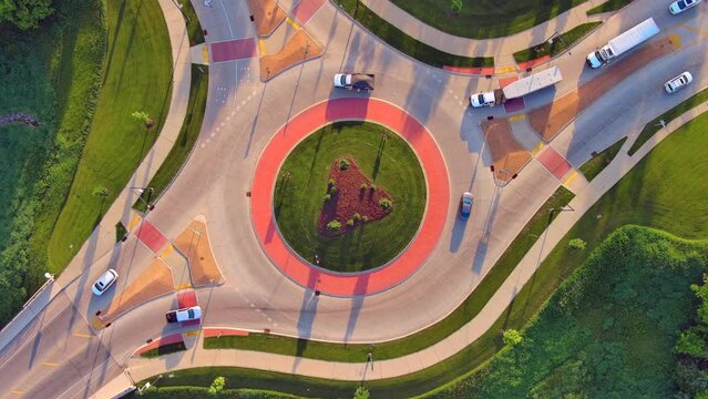 Traffic speeding through roundabout intersection in American Heartland, time lapse aerial view.

