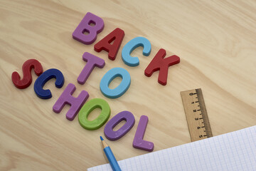 the phrase back to school is laid out in multicolored letters on the table next to a pencil ruler and a notebook with the concept of education school