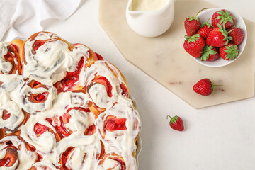Baking dish with strawberry cinnamon rolls and cream on white background