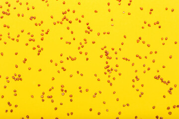 Scattered buckwheat grains on yellow background