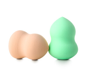 Beige and green makeup sponges on white background