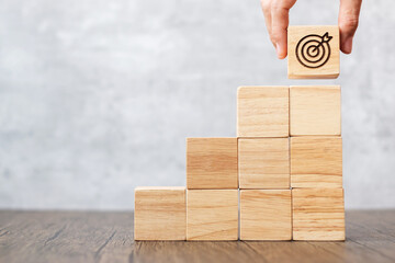 hand hold dartboard block over stack of building with business goal, strategy, target, mission, action, objective, aim and success concept