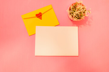 
Greeting card mockup with yellow envelope with heart on pink background