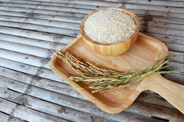 Fototapeta na wymiar White rice (Thai Jasmine rice) on wooden bowl and wooden plate Put on a bamboo table.