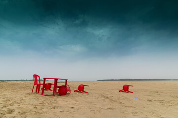 Fototapeta na wymiar Chairs and tables are fallen off after a storm at Tajpur sea shore, West Bengal, India. Moody natural image wirh copyspace.